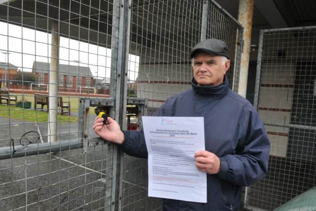 Les Crosby with a copy of the rule changes next to the padlocked gate to the bowling greens.