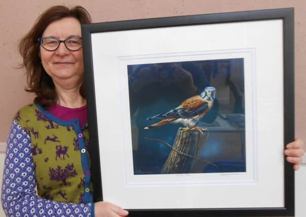 Jenny Lowe with one of her husband's paintings. Graham Lowe's ornithological pictures are on display at Garstang Arts Centre until early April.
