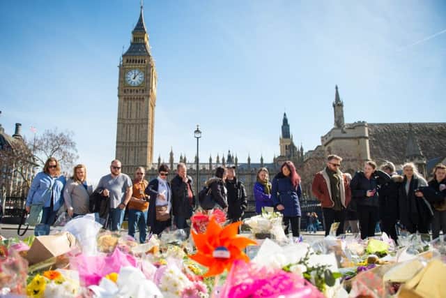 People view floral tributes to the victims of the Westminster terrorist attack on the gates of the Palace of Westminster, London.