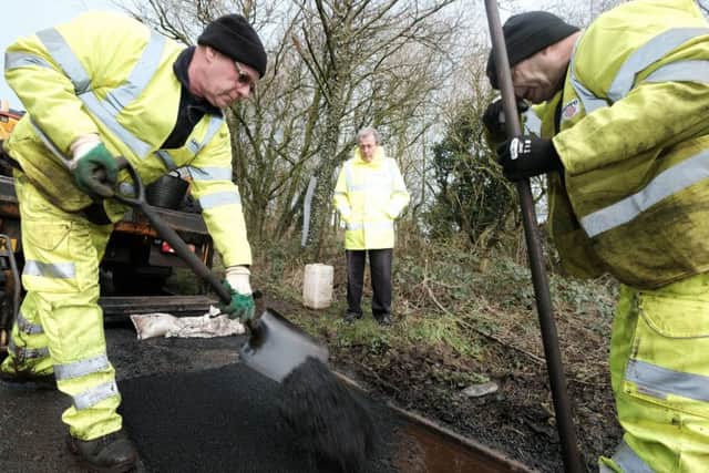 County Coun Keith Iddon  watches repairs in progress during a pothole repair on Moss Side Lane, Chipping