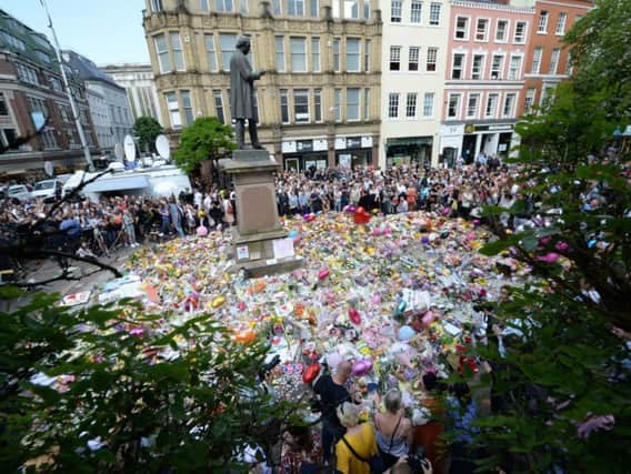 Crowds look at the floral tributes in St Ann's Square, Manchester, to remember the victims of the terror attack