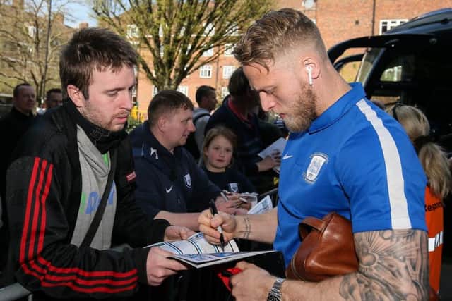 The PNE captain signs at autograph for a fan ahead of the win at QPR