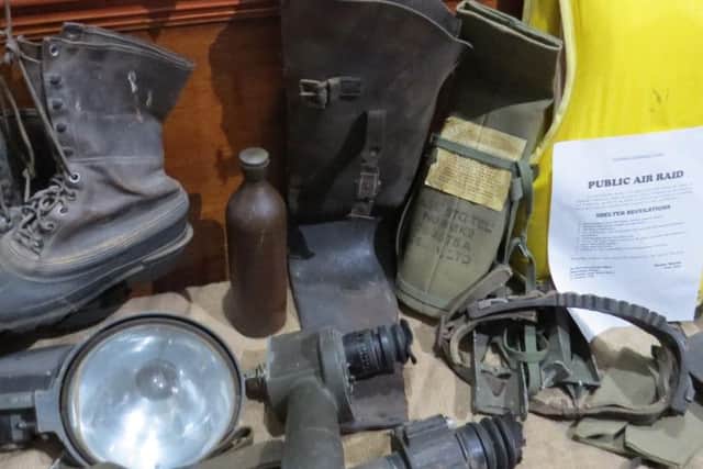 A display of items used in an air raid shelter, including boots, a water bottle, searchlight and harness from John Higginsons collection