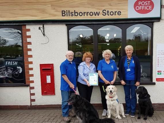 Sharon Rimmer, post mistress at Bilsborrow Post office, receiving a framed certificate from Guide Dogs from dogs Frank Noah and Willow andvolunteer dog handlers Janet Hilton, Sue Ballantyne and Russ Evans