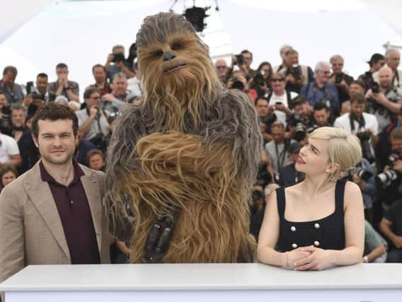Actor Aiden Ehrenreich, from left, a person wearing a costume of the character Chewbacca and actress Emilia Clarke